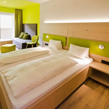 Schlössle Modernes Hotelzimmer mit zwei Einzelbetten, Holzmöbeln und grünen Akzenten